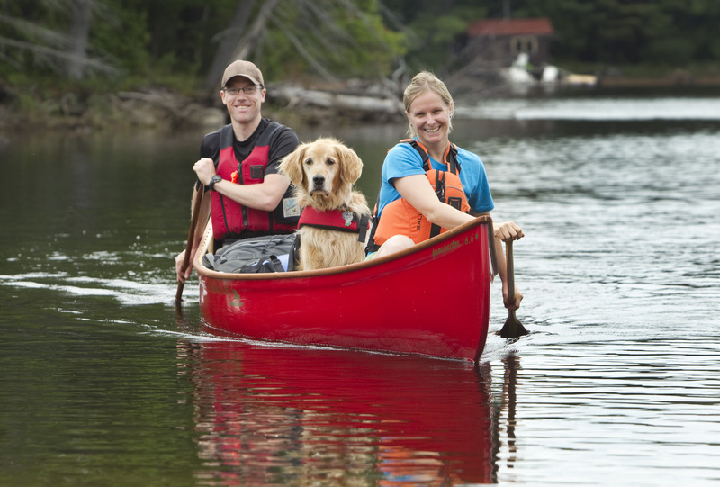 image of man, women and dog in canoe