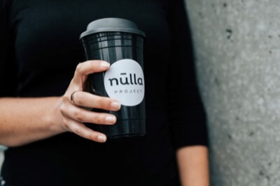A close-up of a hand holding a Nulla coffee