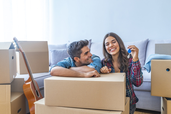 young couple holding key leaning on cardboard boxes 1077270538