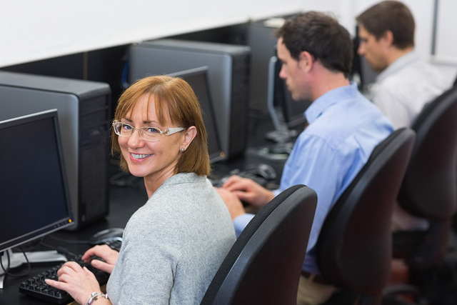 Woman seated in front of a computer in a lab, looks at the camera.