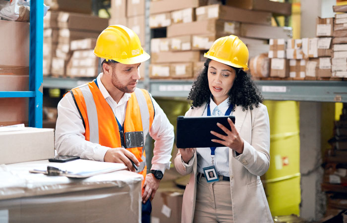 Two people in a warehouse looking at a tablet