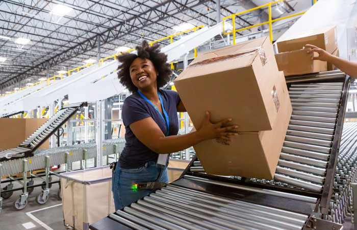 A woman grabbing boxes off a conveyor belt in a warehouse