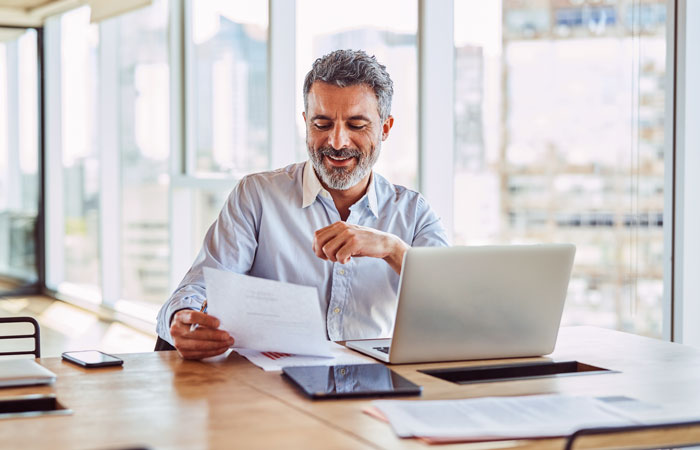 a man sitting at his desk working looking at a paper