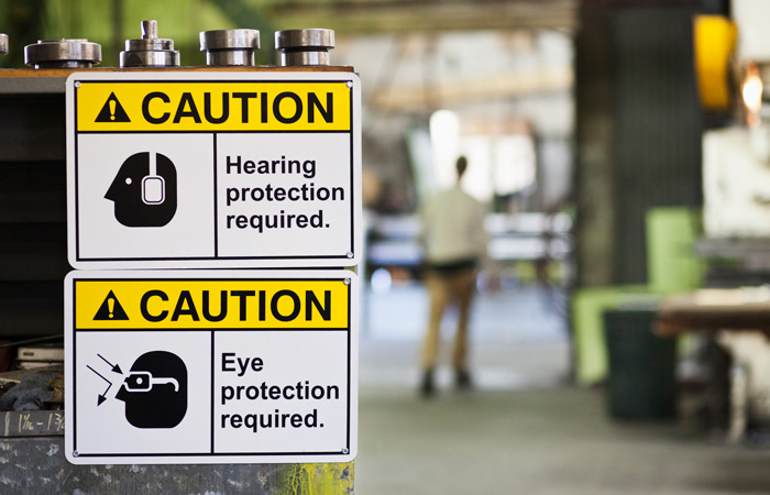 A close-up of hearing protection and eye protection required signs in a warehouse