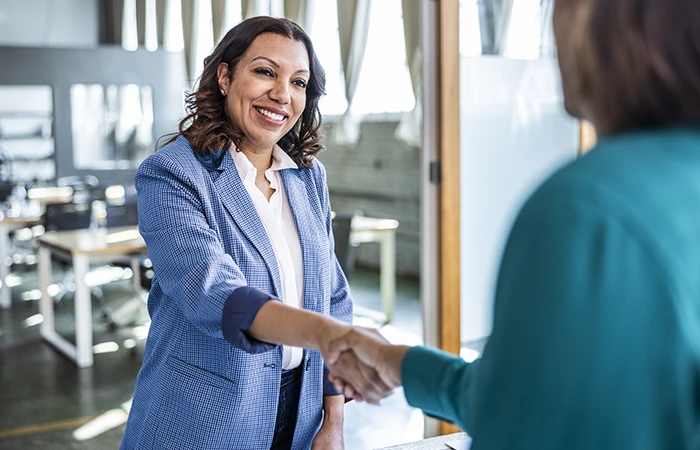 Two people working in an office shaking hands