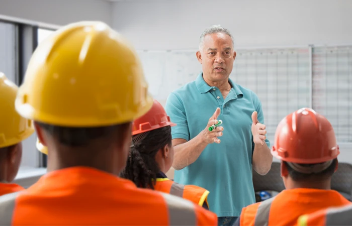 Person giving a safety talk to a group of construction workers