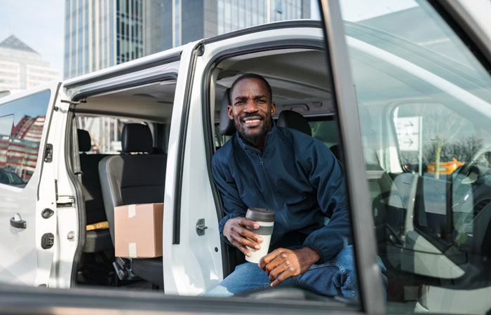 A man sitting in his work vehicle having a coffee