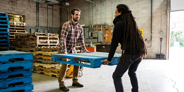 Man and woman lifting pallet together in warehouse