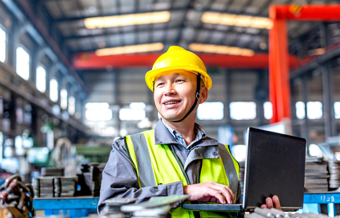 An employee in a warehouse working on a laptop