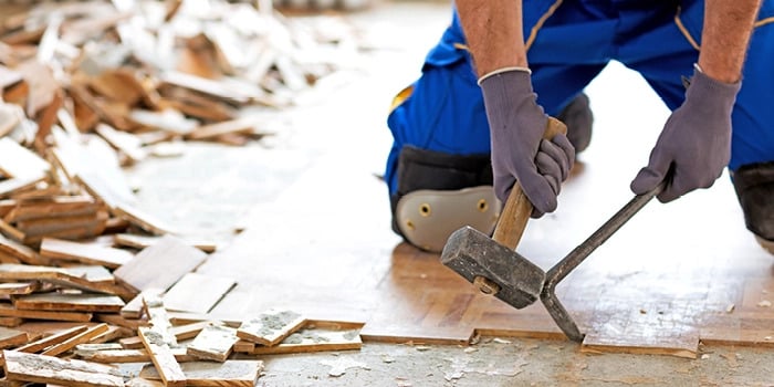Person using a hammer to remove flooring