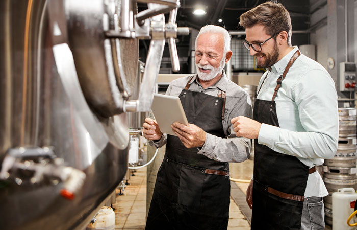 Two brewers working looking at a tablet