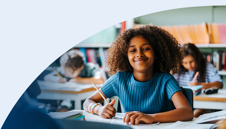 girl sitting at desk writing with pencil