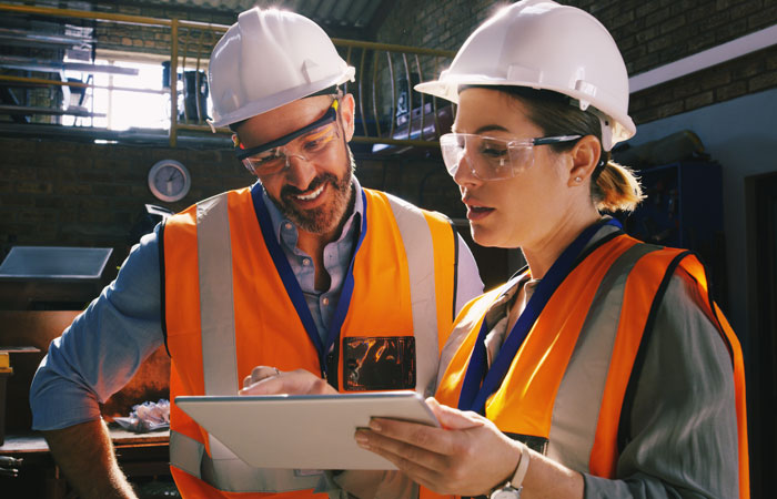 Two people in hi-vis safety gear working on a tablet