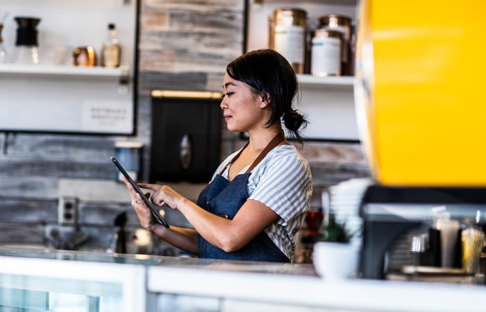 A woman in a coffee shop looking at a tablet