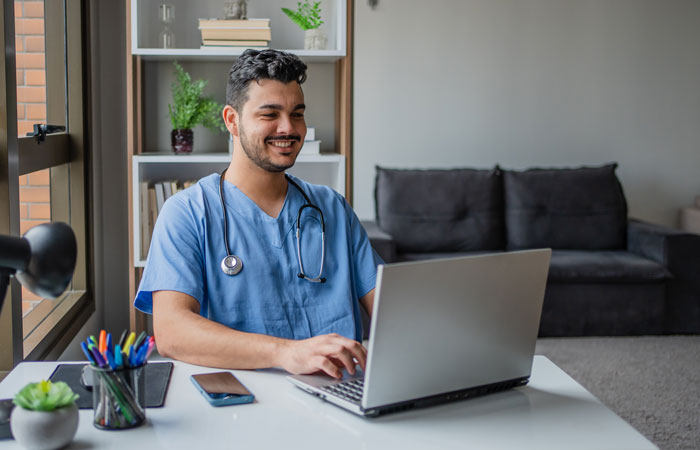 A medical worker sitting down working on a laptop in their office