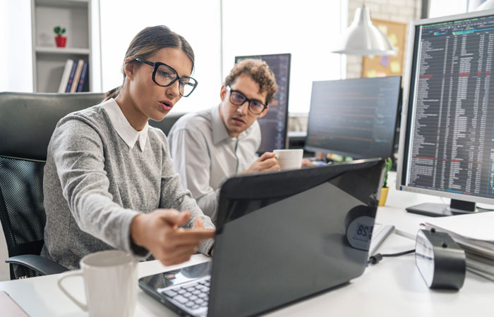 Two people working at a desk looking at a laptop