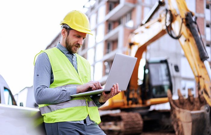 A man working on a laptop on a construction site