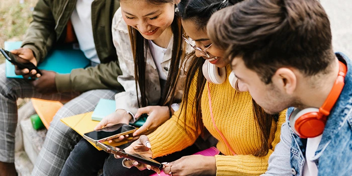 high school students laughing while looking at phones together