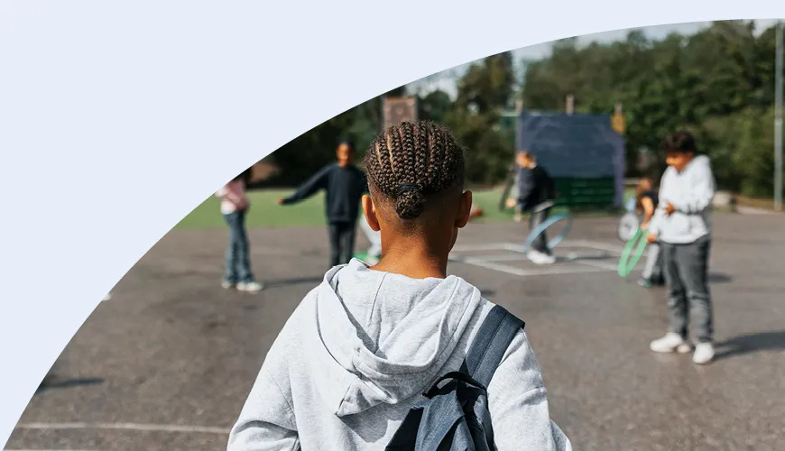 boy standing on playground with other kids staring at him
