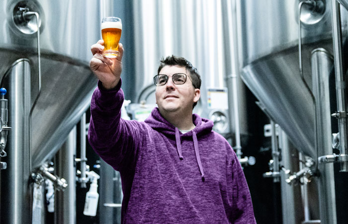 a person holding up a glass of beer at a brewery