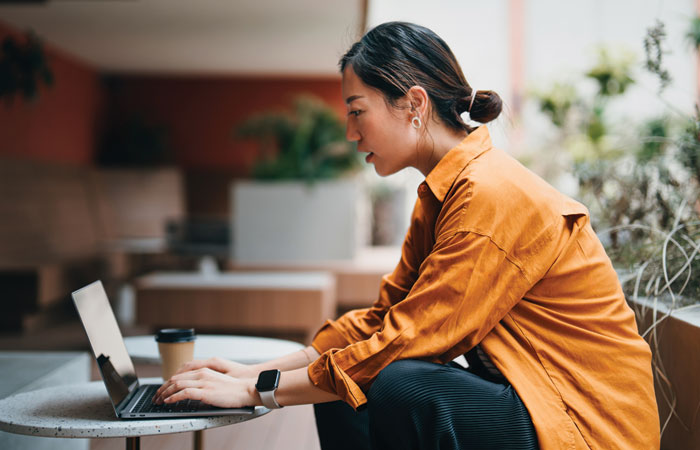 A woman sitting down working on her laptop