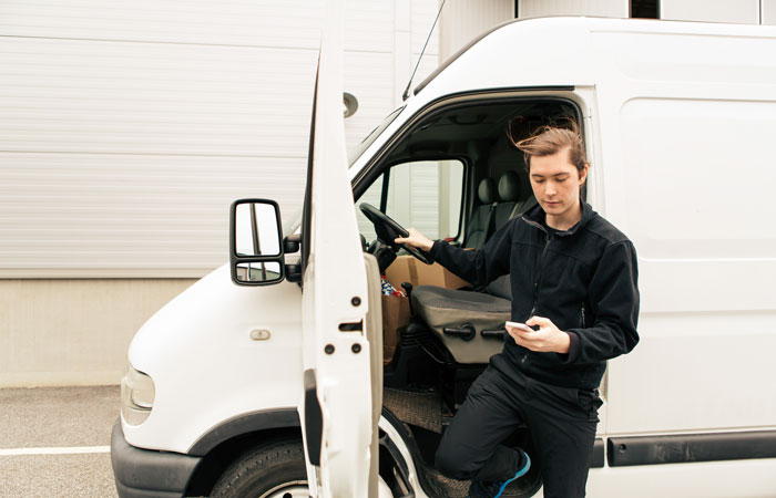 A driver looking at their mobile device while stepping out of their vehicle