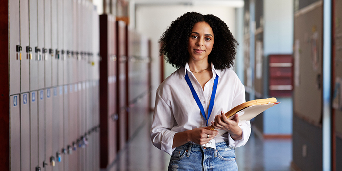 teacher standing in school hallway holding a clipboard