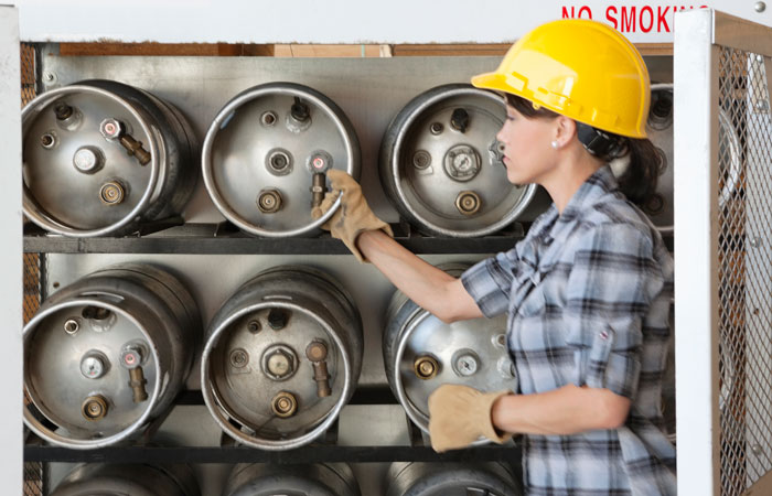 A woman checking the pressure on tanks on a shelf