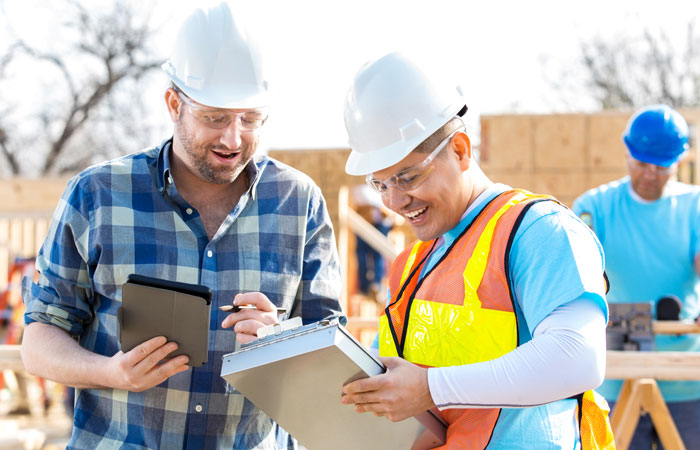 Workers in hard hats looking over documents in a construction site