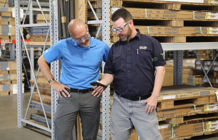 Two men in a warehouse looking over data on a mobile device