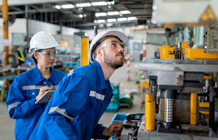 two workers inspecting a machine