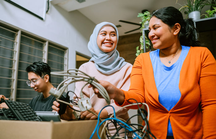 Two people sorting through a box of electronics