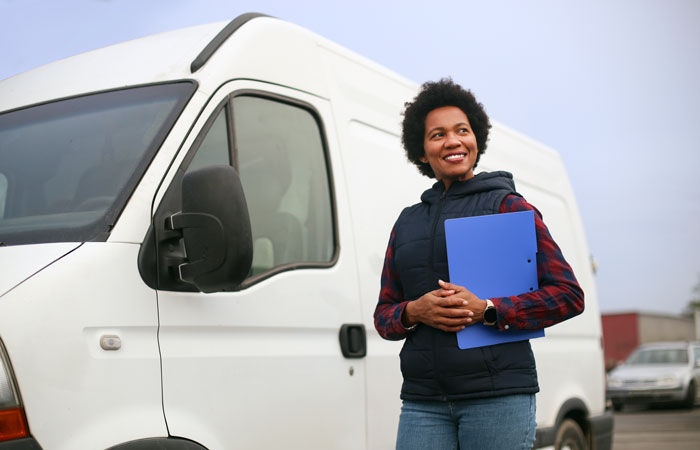 A woman with a folder standing in front of a commercial van