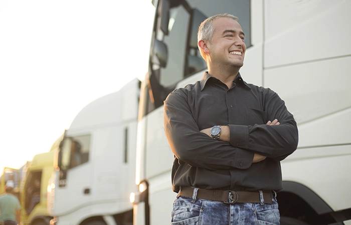 A driver standing in front of a work truck smiling