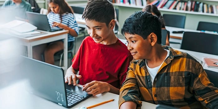 two students looking at a laptop computer