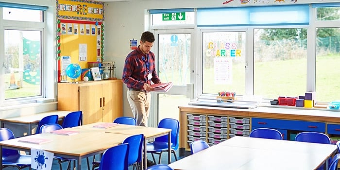 teacher passing out books in classroom