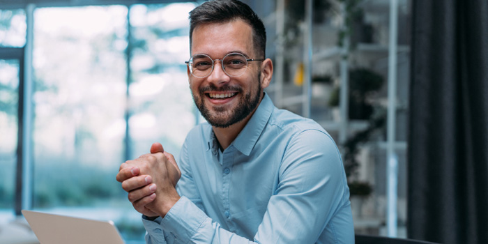 Man in glasses sitting at a desk smiling