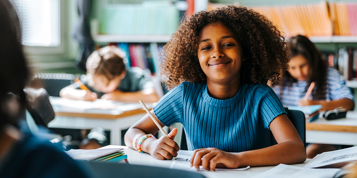 girl sitting at desk writing with pencil