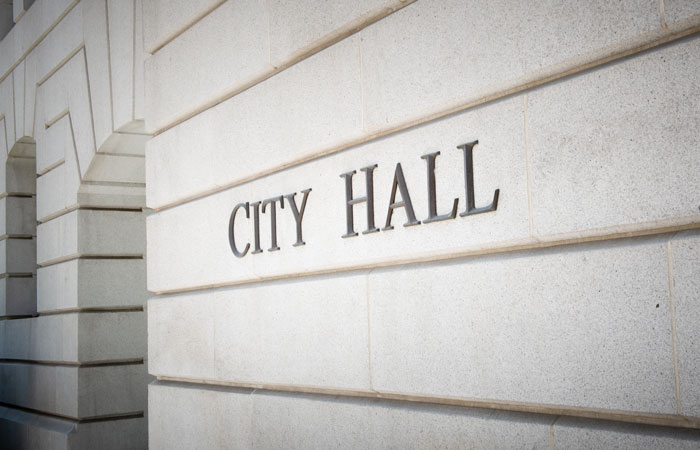 Close up of a building with the words city hall on the exterior wall of the building