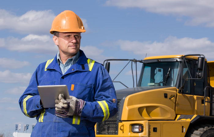 A worker standing in front of construction equipment