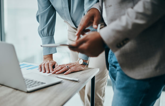 Close up of two people working in front of a laptop and a smart phone
