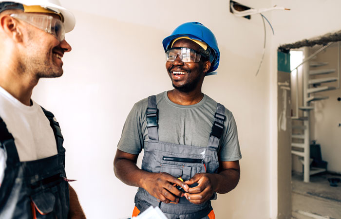 Two construction workers smiling at each other at a work site