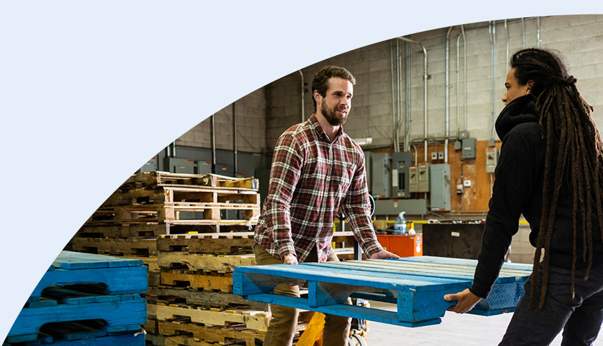 Man and woman lifting pallet together in warehouse