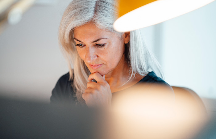 A woman looking down working underneath a lamp