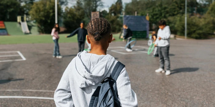 boy standing on playground with other kids staring at him