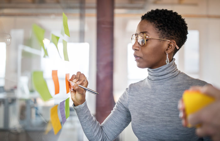 A woman writing on a sticky note on a glass window