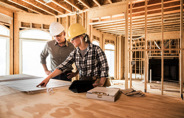 Contractors looking over plans in a framed house