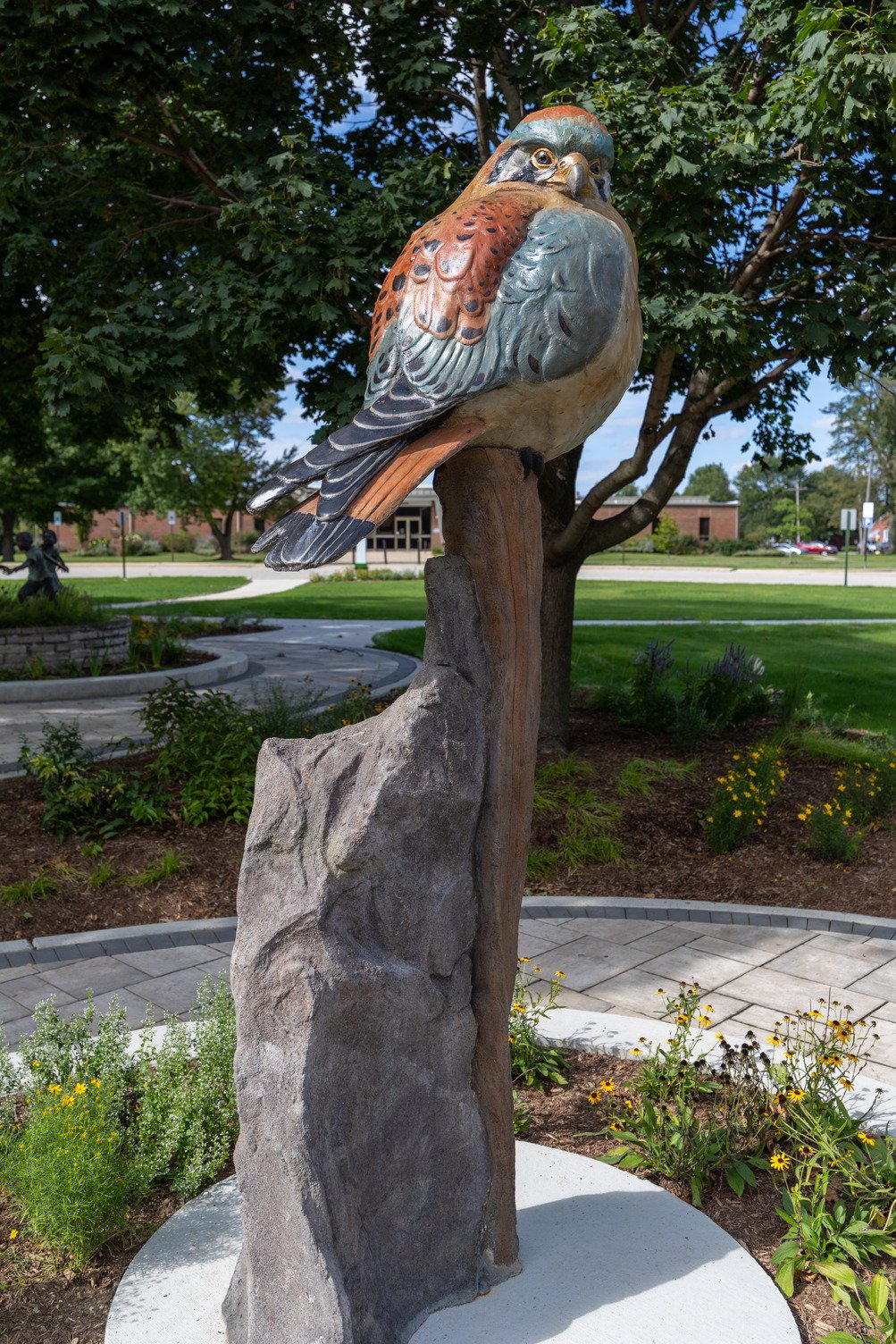  8.5’ tall colored concrete sculpture of an American Kestrel perched upon a tree-like base