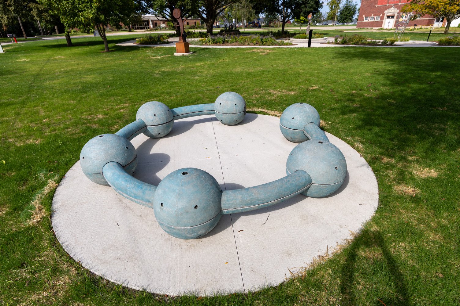 a large circular concrete sculpture, 12’ in diameter, which includes an opening and a series of globes 