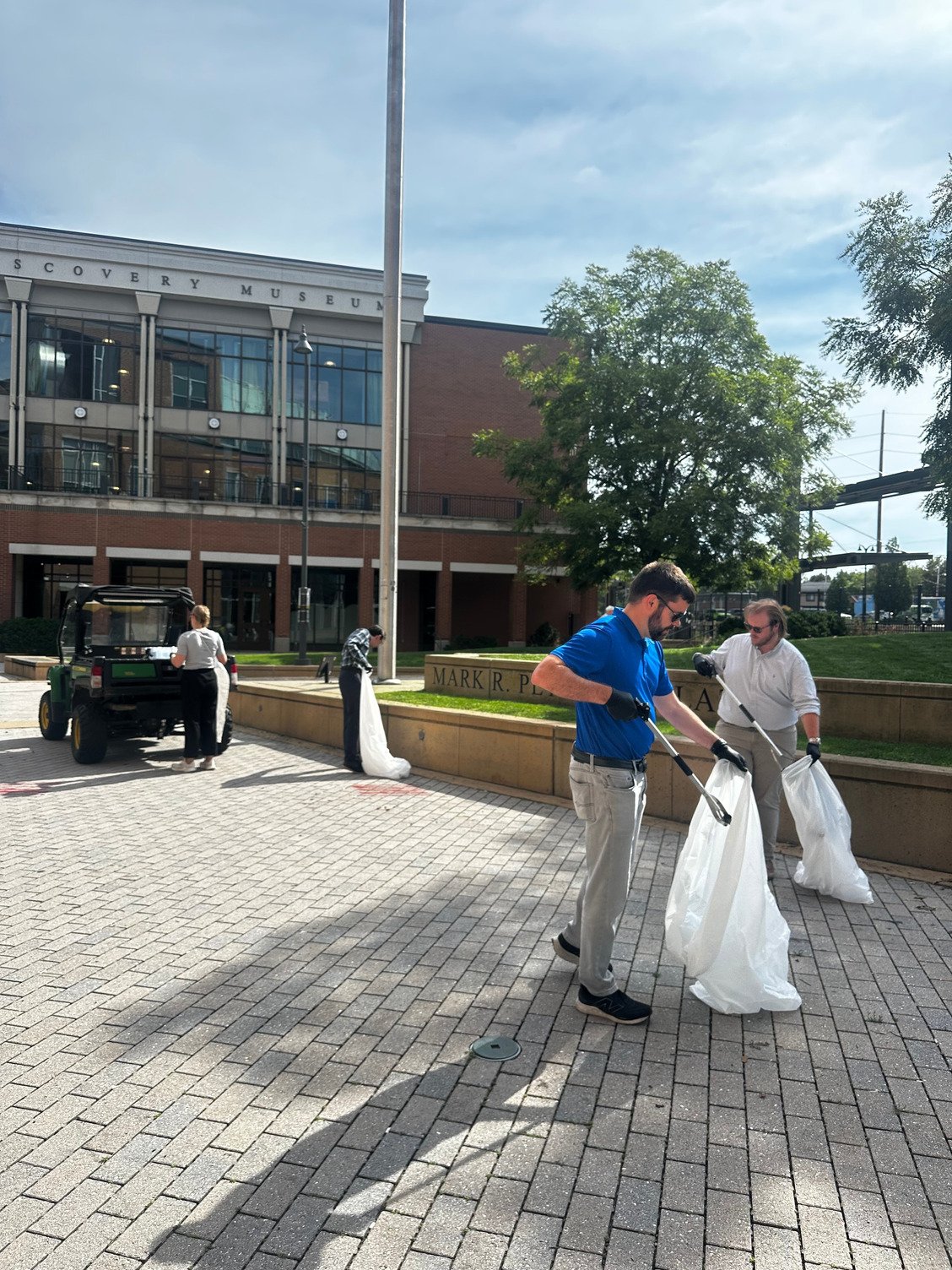 people with grabbers and trash bags picking up trash in Mark Peterson Plaza
